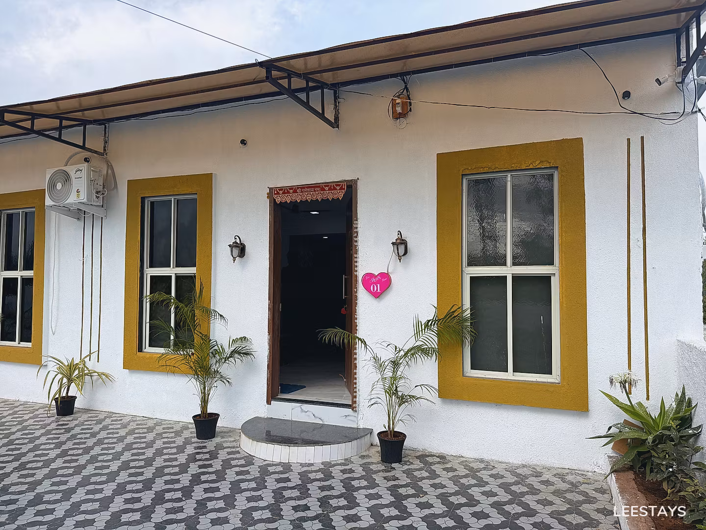 White building exterior with yellow window frames and an open doorway.