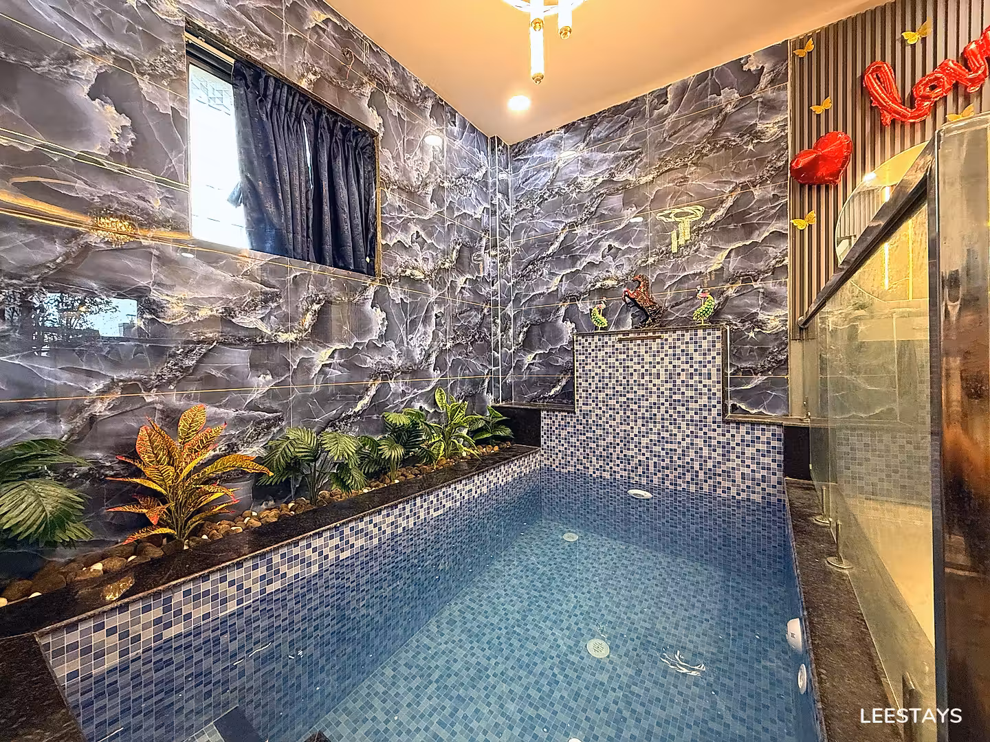 Indoor plunge pool with tiled walls and decorative plants.
