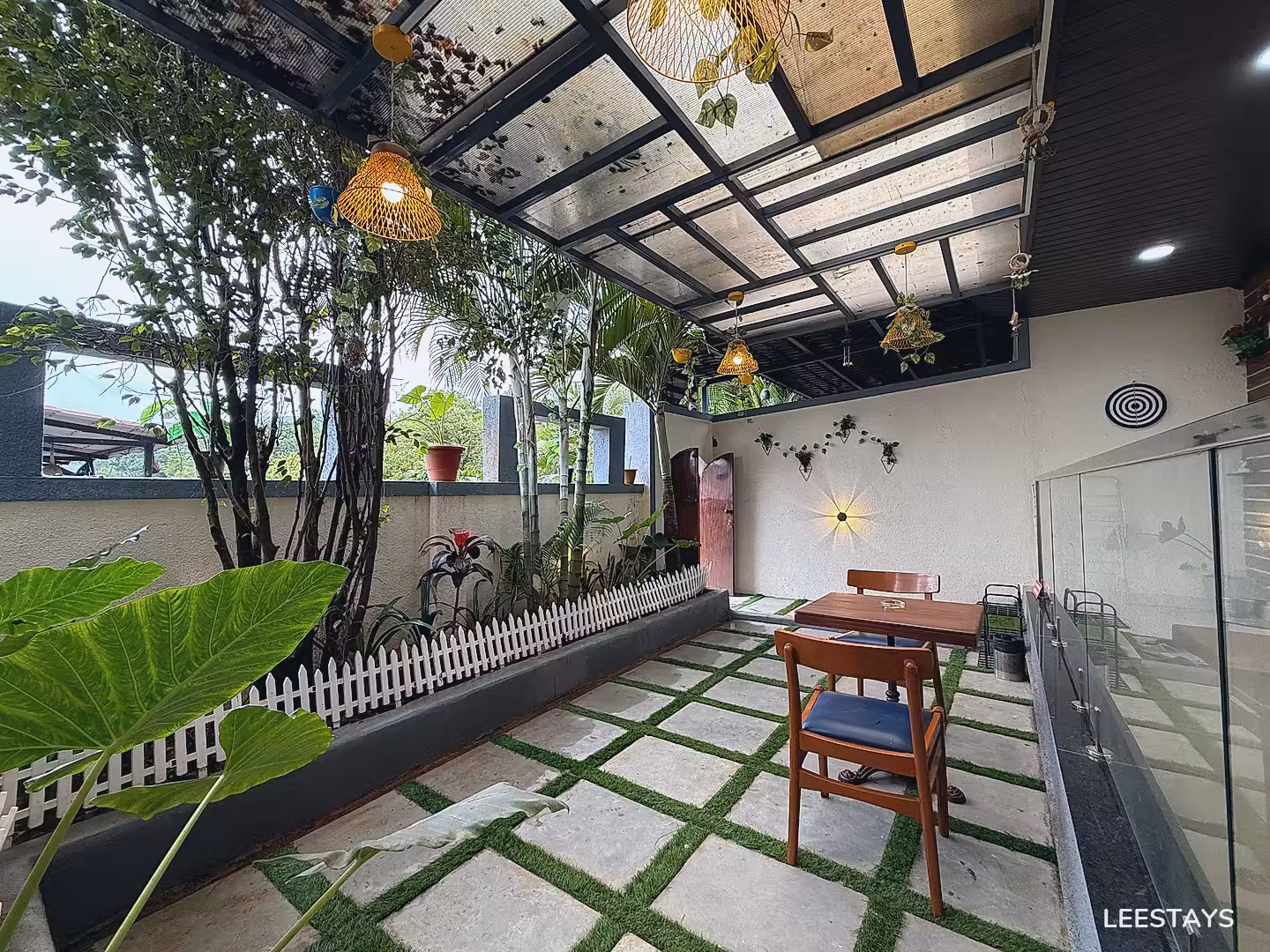 Covered outdoor seating area with a table, chairs, and plants.