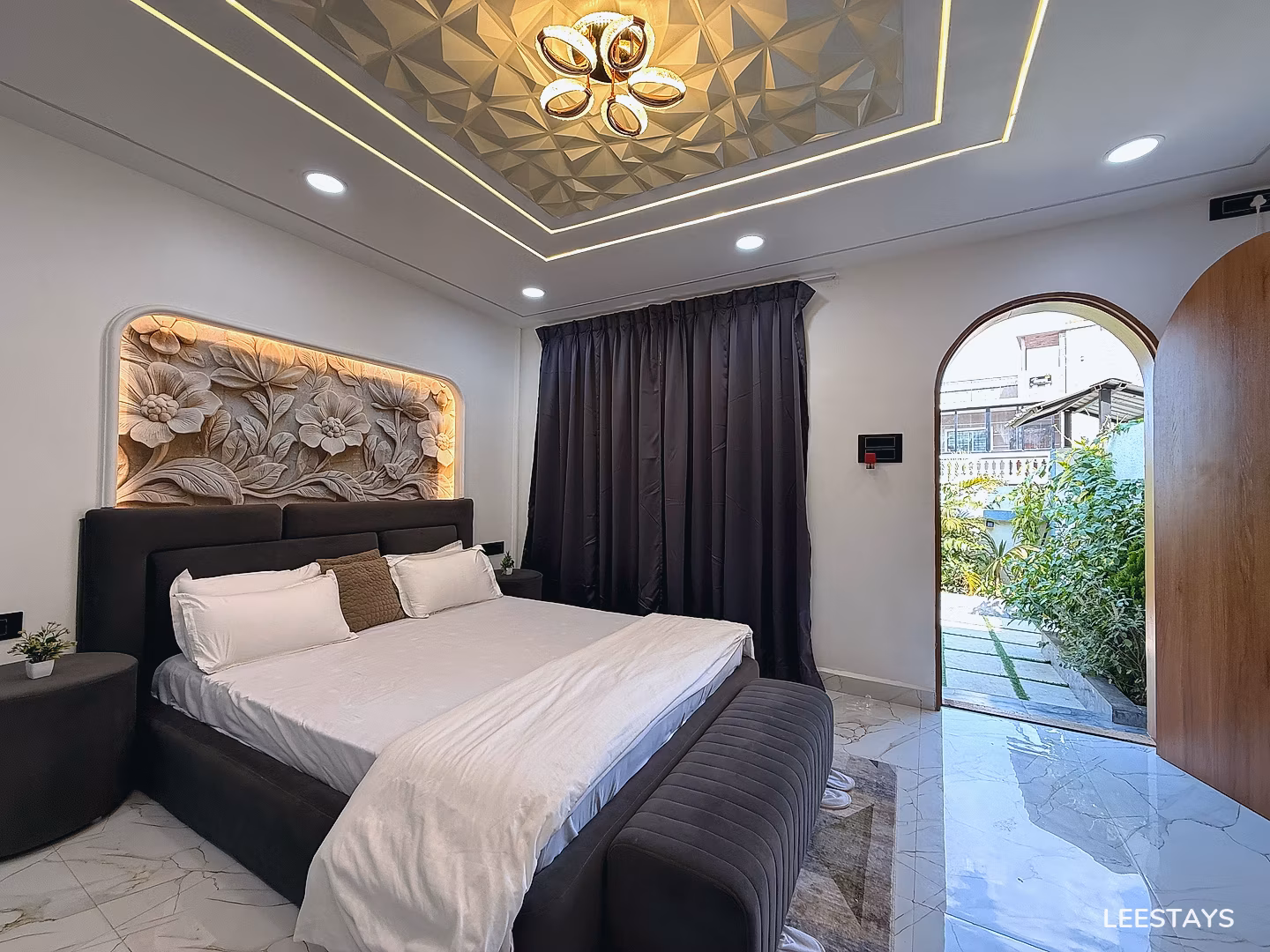 Bedroom with a large bed, carved headboard, and an arched doorway leading outside.