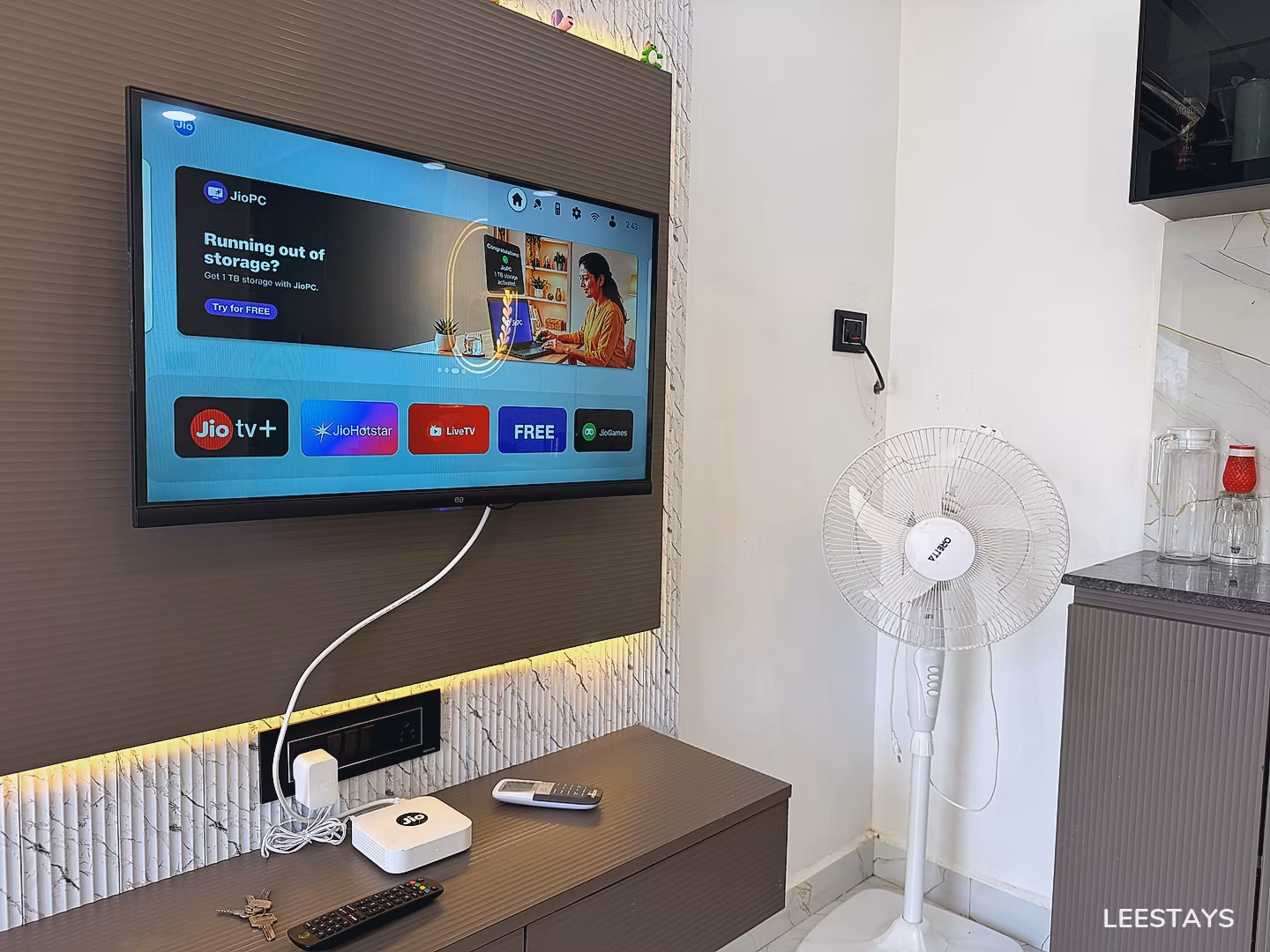 Television displaying media applications and a white oscillating floor fan.