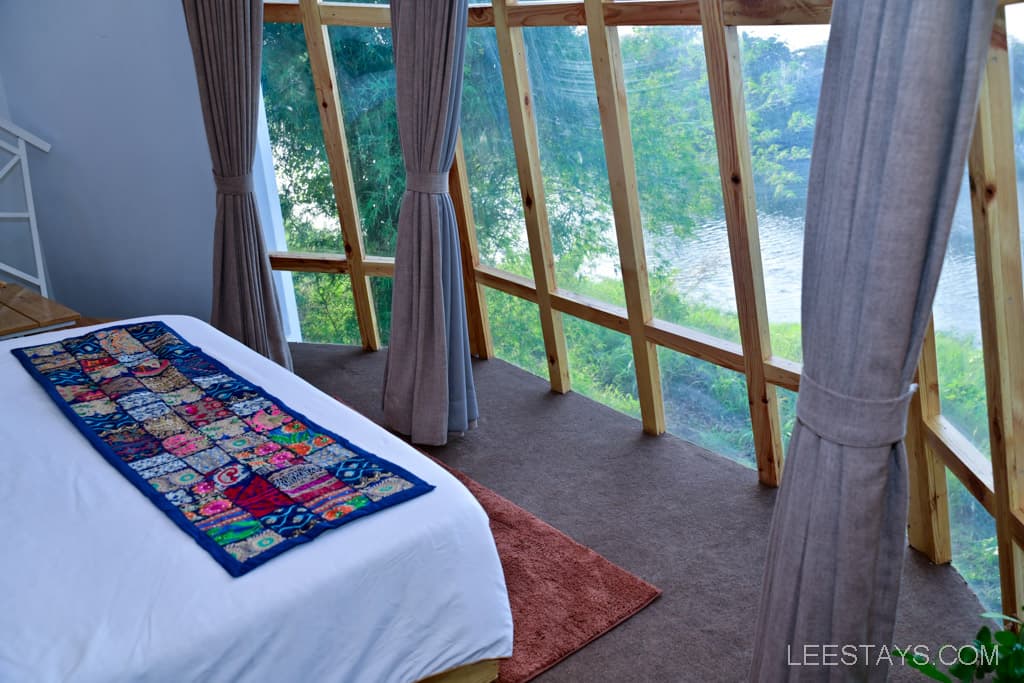 A bedroom featuring a bed with a colorful textile spread across it and large windows allowing natural light.