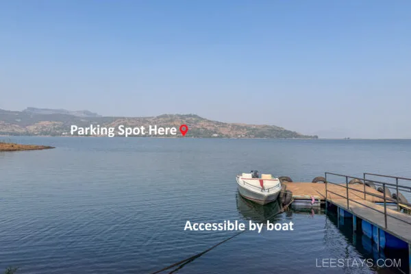 A serene view of Pawna Lake with text indicating 'Parking Spot Here' on the opposite shore and 'Accessible by boat' near a small docked boat.